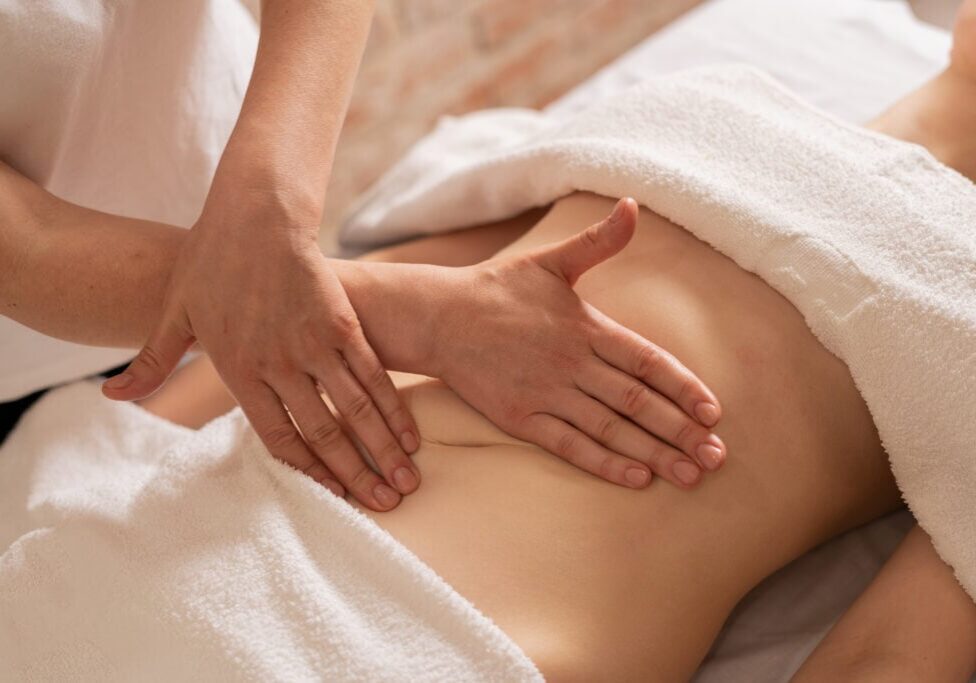 relaxing massage and body shaping massage, lymphatic drainage, manual and aesthetic procedures, hands massaging belly in the spa salon